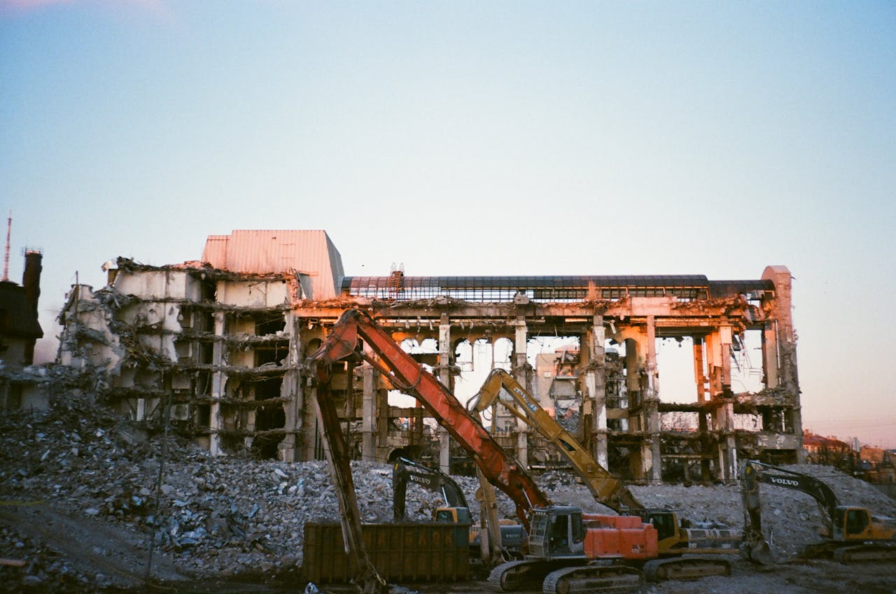 Construction machinery at a building demolition site during sunset.